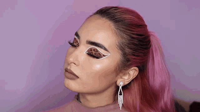 a woman with pink hair is wearing a ponytail and earrings