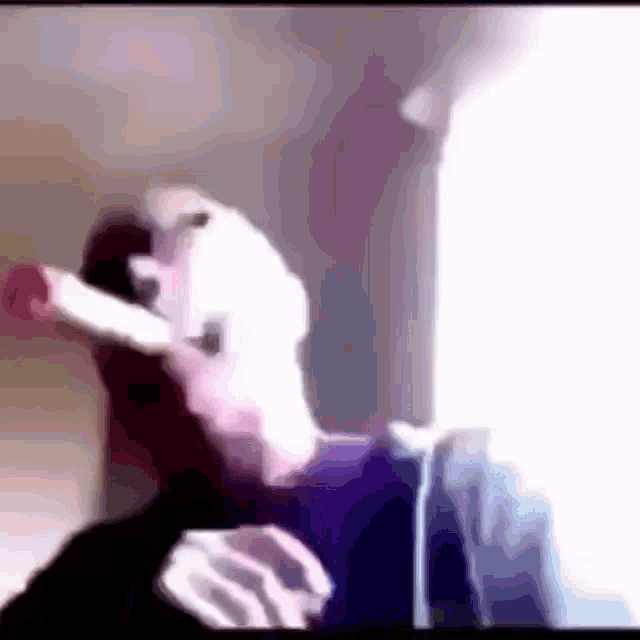 a man in a purple shirt is smoking a cigarette in a blurry photo .