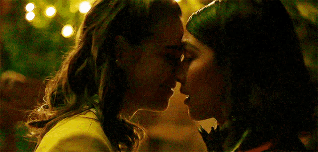 a couple of women are kissing each other on the forehead .