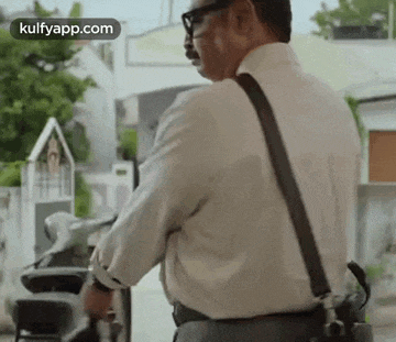 a man in a white shirt and suspenders is standing next to a scooter .