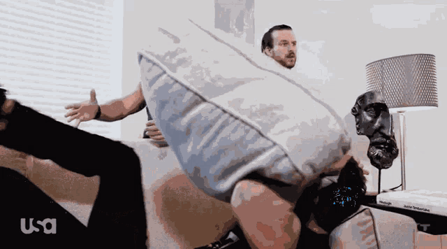 a man is holding a pillow over another man 's head with usa written in the corner