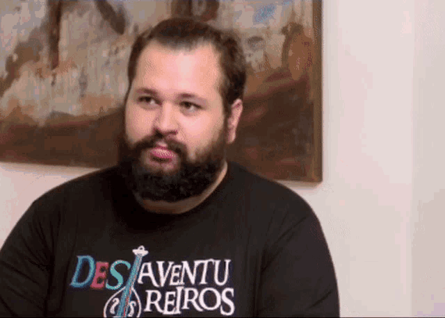 a man with a beard wearing a black shirt that says des aventu reiros