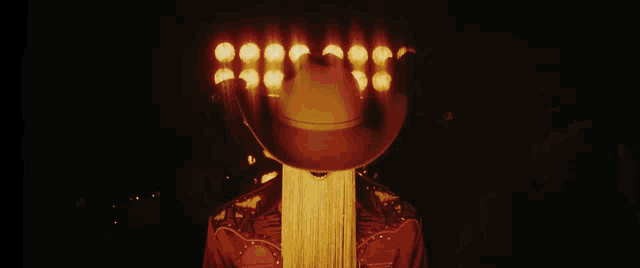 a man in a cowboy hat is standing in front of a row of lights .