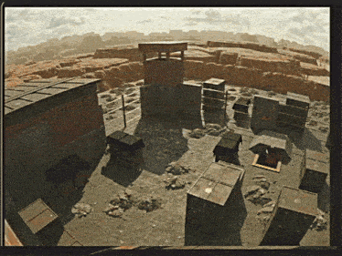 an aerial view of a desert landscape with boxes and a building in the background