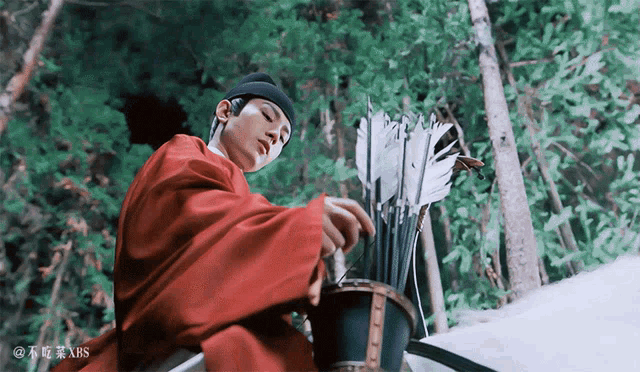 a man in a red robe is holding a bucket of arrows