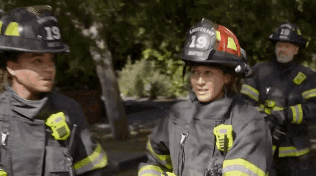 a group of firefighters are standing next to each other wearing helmets .