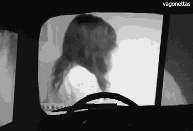 a woman is sitting in a car looking out the window .