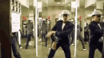 a man in a suit is dancing in front of a mirror while wearing a hat with the letter s on it