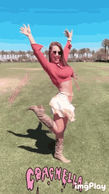 a woman in a red top and white skirt is standing in a field with her arms in the air