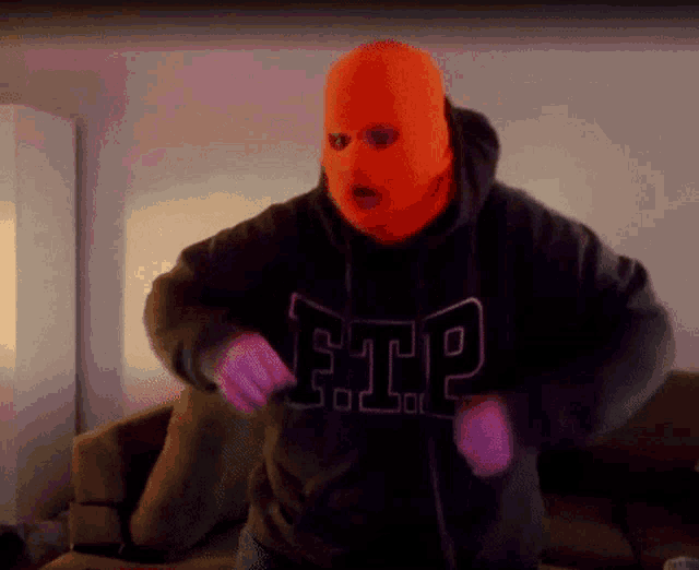 a man wearing an orange ski mask and a black hoodie with the word ftp on it