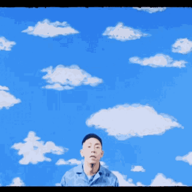 a man stands in front of a blue sky with clouds
