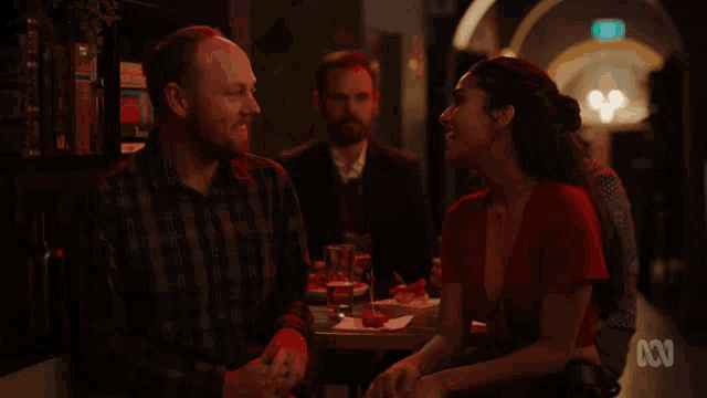 a man in a plaid shirt sits at a table with a woman in a red top and the letters 00 on the table