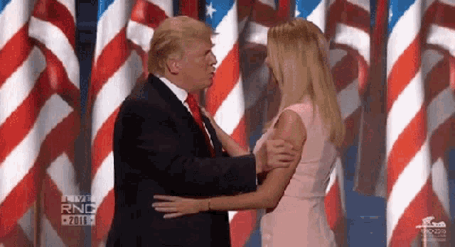 a man in a suit and tie is hugging a woman in a pink dress .