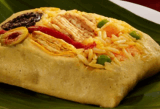 a close up of a sandwich with rice and vegetables on a banana leaf
