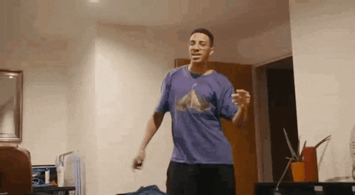 a man wearing a purple shirt is dancing in a living room .