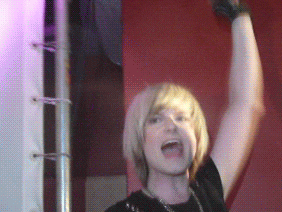 a woman with blonde hair holds her arm in the air