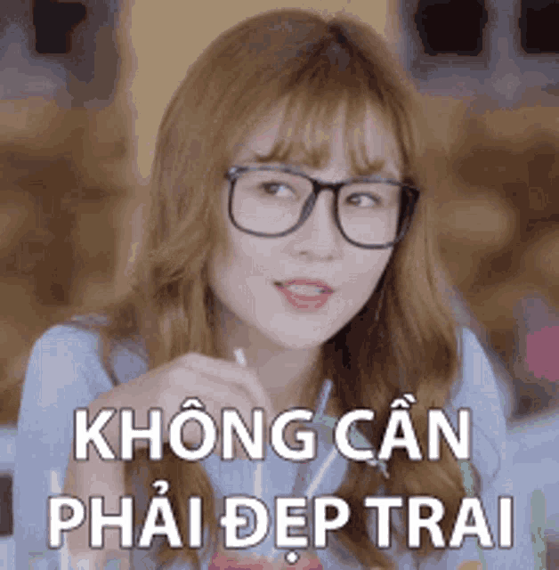 a woman wearing glasses is sitting at a table with a drink in her hand and says không can phải đẹp trai