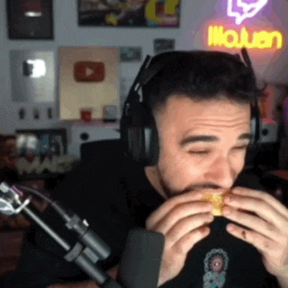 a man wearing headphones is eating a hamburger in front of a neon sign that says ' youtube '