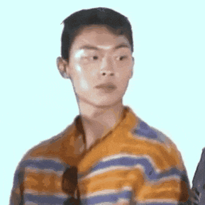 a young man wearing a striped shirt is looking at the camera .