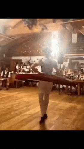 a man is dancing on a wooden floor in a room with people sitting at tables .