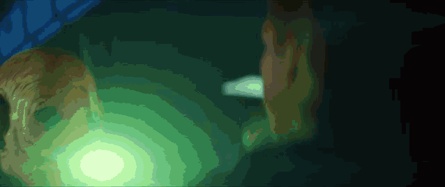 a green light is shining on a person 's face in a dark room
