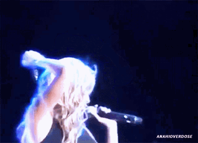 a woman singing into a microphone with a blue light behind her and the words anahioverdose below her