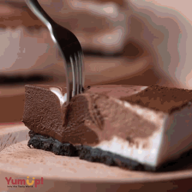 a piece of chocolate cake is being eaten with a fork from yum up