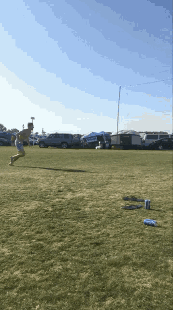 a man running in a field with a blue can of bud light in the grass