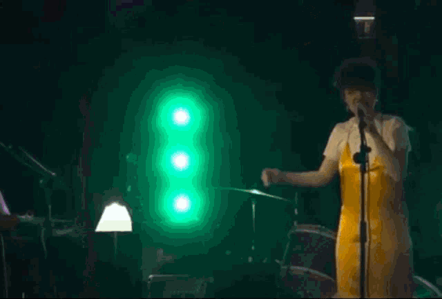 a woman in a yellow dress singing into a microphone on stage
