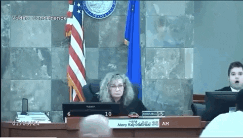 a woman is sitting at a desk with a sign that says mary keysmith on it