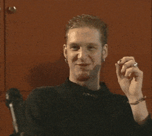 a man in a nypro shirt is smiling and holding something in his hand