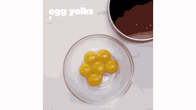 a glass bowl filled with yellow eggs next to a pan of brown liquid .