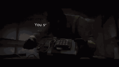 a man is holding a bomb in his hand and talking on a cell phone in a dark room .