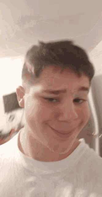 a young man wearing a white shirt is smiling for the camera .