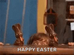 a boy is sitting at a table with chocolate bunnies in front of him and says `` happy easter '' .