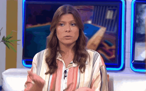 a woman in a striped shirt talks into a microphone on a television