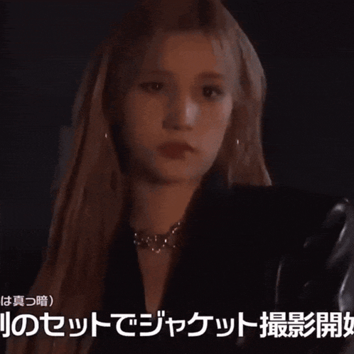 a woman in a black jacket with chinese writing on the bottom of the image