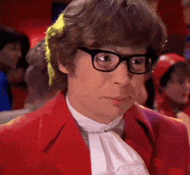 a man wearing glasses and a red jacket looks serious