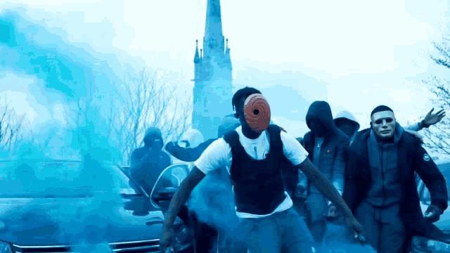 a man with a mask on his head stands in front of a car