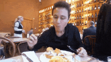 a man is sitting at a table with a plate of food and a knife and fork