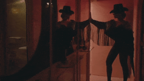 a woman wearing a cowboy hat and fringe jacket is standing in front of a mirror
