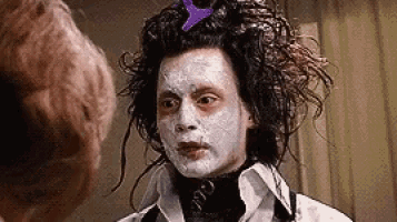 a man with white paint on his face is standing next to another man .