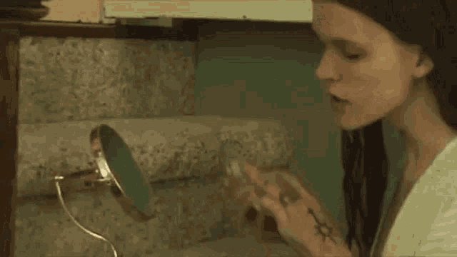 a woman is applying lipstick in front of a mirror in a bathroom .