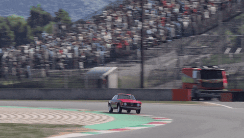 a red car is driving down a race track with a crowd in the background