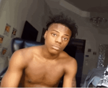 a shirtless man is sitting in a chair and making a funny face .
