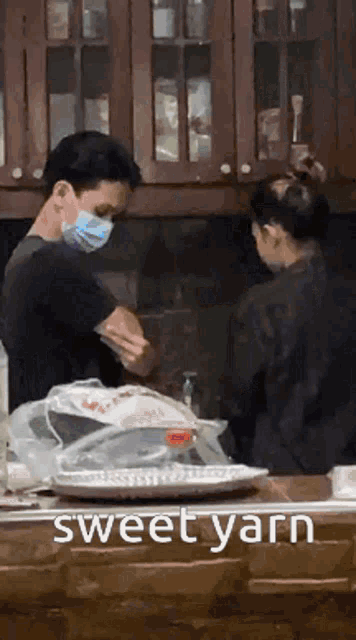 a man wearing a mask is standing next to a woman in a kitchen with the words sweet yarn written on the bottom