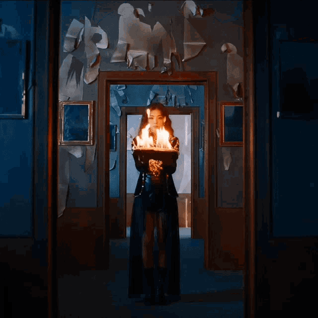 a woman standing in a hallway holding a candle