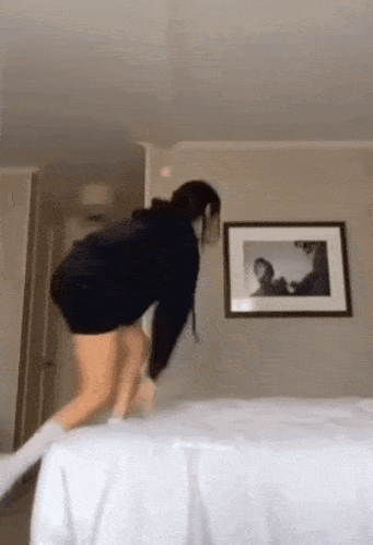 a woman is standing on top of a bed in a room .