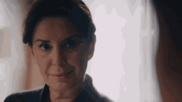 a woman is smiling and looking at the camera