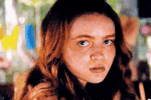 a close up of a young woman making a funny face while looking at the camera .